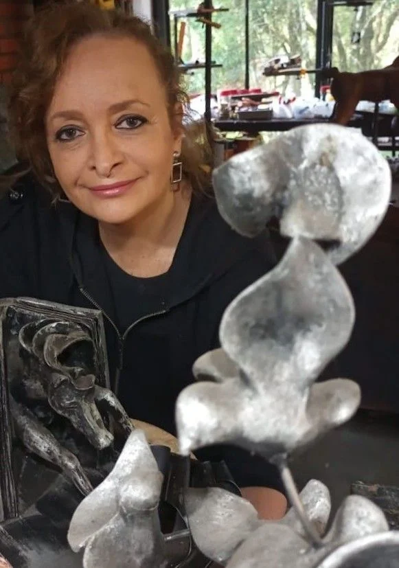 A artista Débora Irion em seu ateliê, ao lado de esculturas